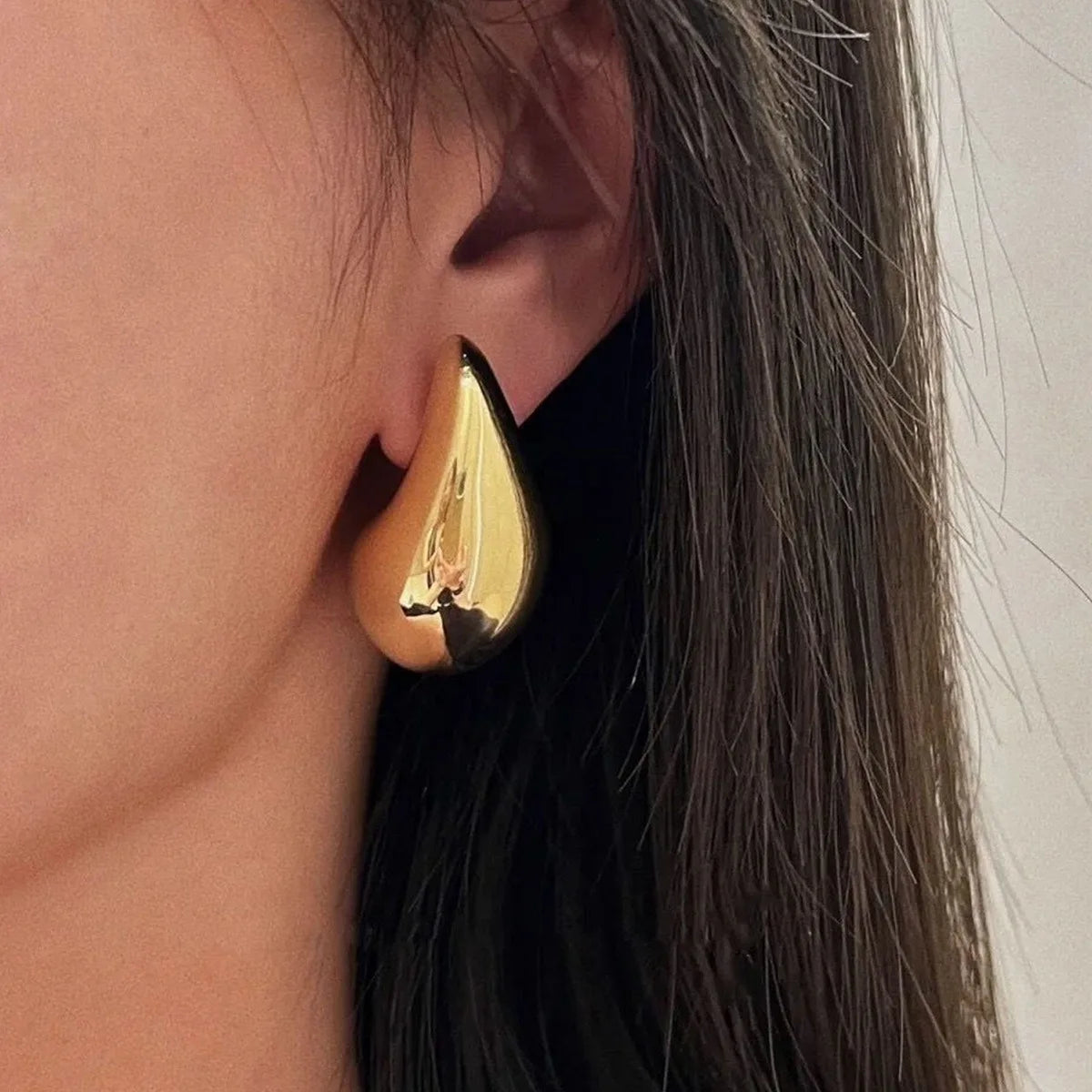 These are  golden, chunky water drop dome stud earrings for women. They're  metal, glossy, thick teardrop-shaped, and designed to be stylish and sexy. Perfect for adding a touch of glamour to your look!