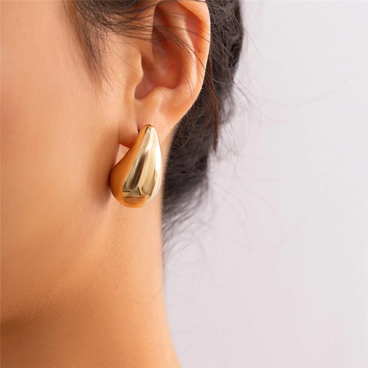 These are  golden, chunky water drop dome stud earrings for women. They're  metal, glossy, thick teardrop-shaped, and designed to be stylish and sexy. Perfect for adding a touch of glamour to your look!