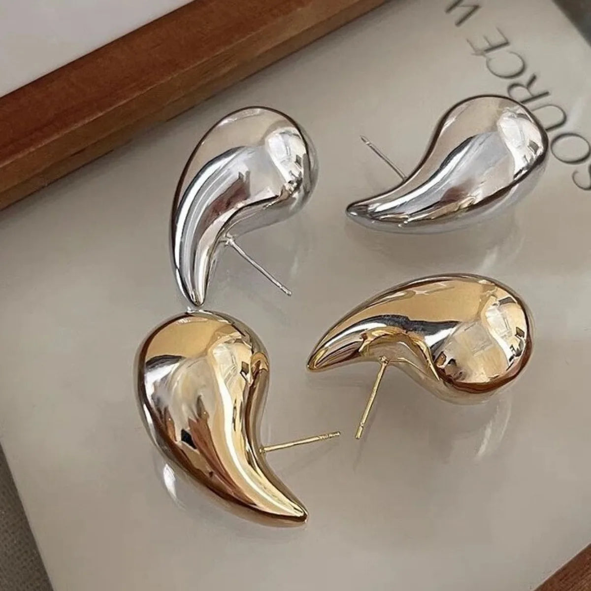 These are  golden, chunky water drop dome stud earrings for women. They're  metal, glossy, thick teardrop-shaped, and designed to be stylish and sexy. Perfect for adding a touch of glamour to your look!