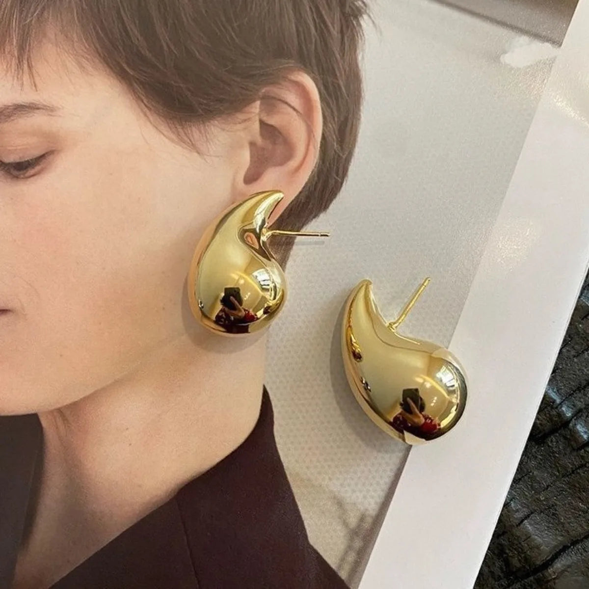 These are  golden, chunky water drop dome stud earrings for women. They're  metal, glossy, thick teardrop-shaped, and designed to be stylish and sexy. Perfect for adding a touch of glamour to your look!